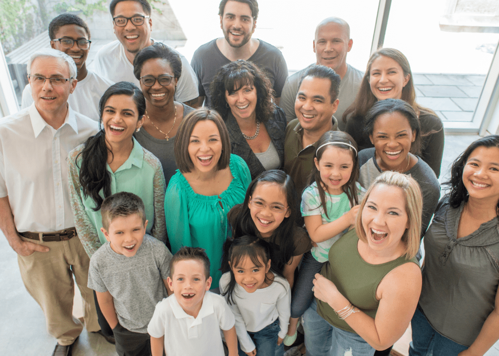 A group of people with different ages smiling. Navigating Business Transitions with Clarity and Confidence.