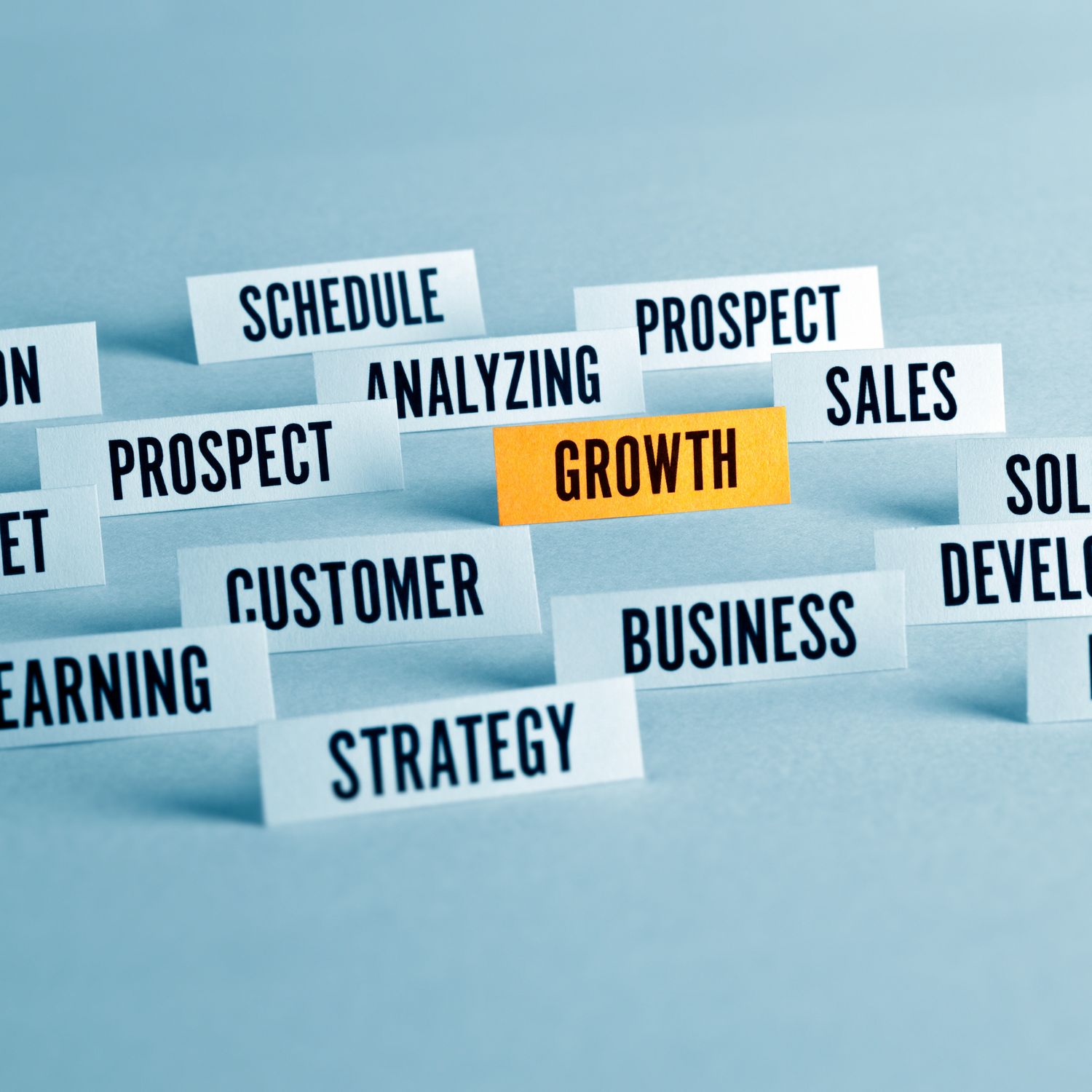Different business terms in light blue background around the word growth in yellow gold background