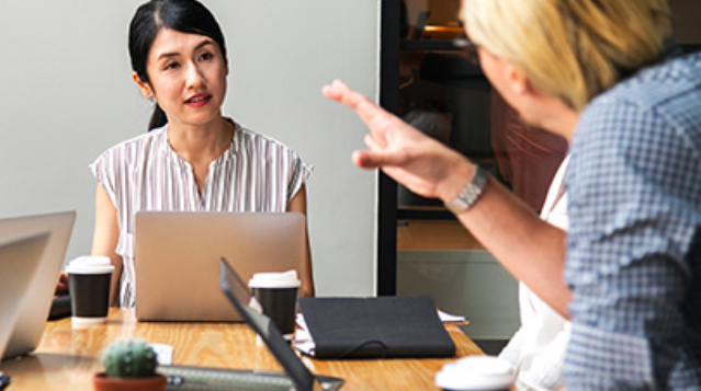 A woman listening to another person across the meeting table